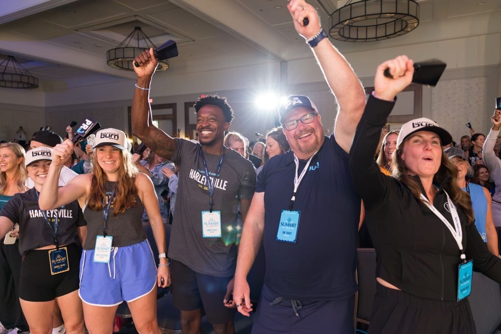 A group of Burn Summit attendees cheer and hold up blue PR bells