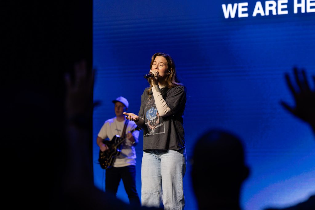 A worship leader sings on stage as attendees worship during Roundup 2026.