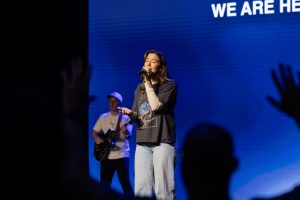 A worship leader sings on stage as attendees worship during Roundup 2026.