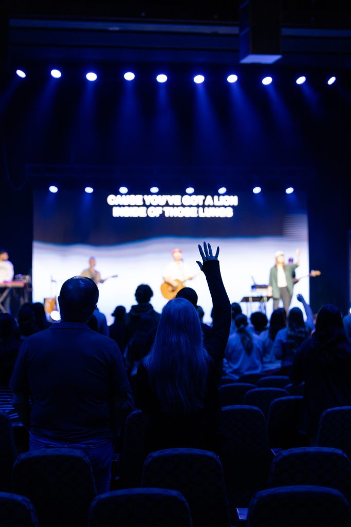 An attendee raises a hand as the worship band leads during Roundup 2026.