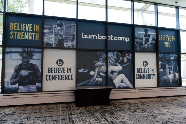 Large Burn Boot Camp window graphics combine athlete photographs, a logo, and messages about strength, confidence, and community.